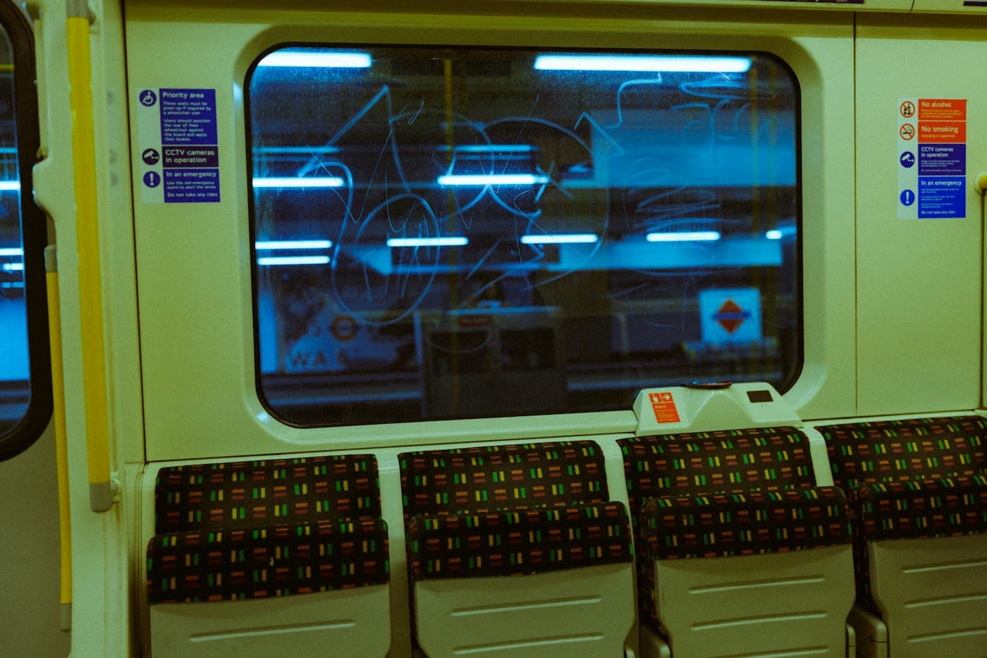 An empty Underground carriage late at night, lit by the platform outside.